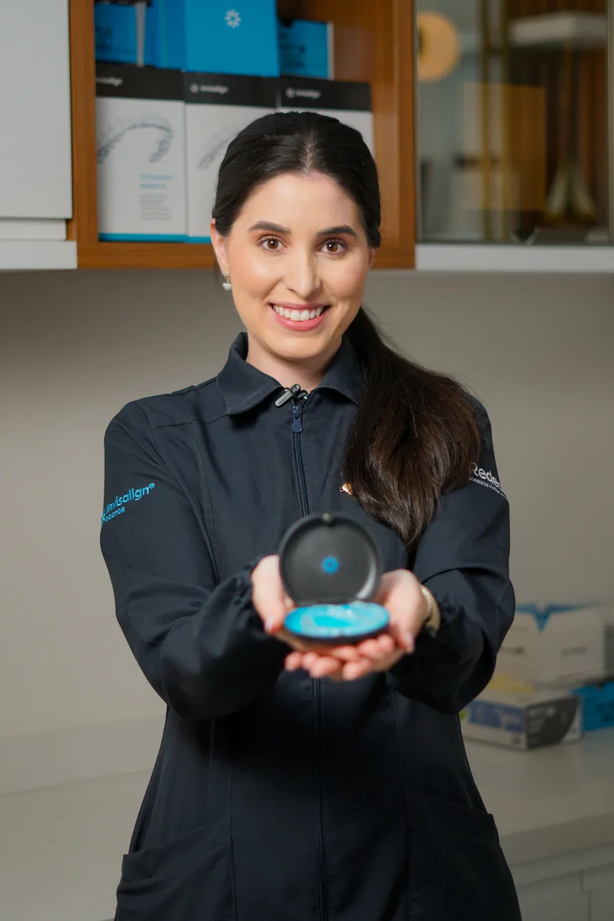 Dra. Juliana Braga segurando um estojo de alinhadores Invisalign